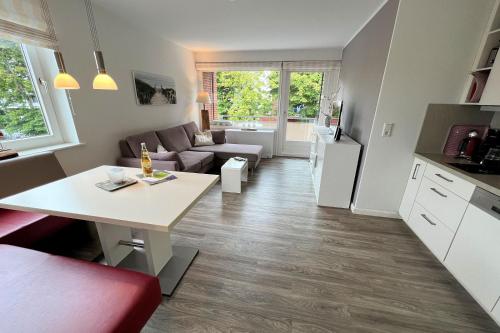 eine Küche und ein Wohnzimmer mit einem Tisch und einem Sofa in der Unterkunft Whg Lütt Lee Sandwall 60 Wyk in Wyk auf Föhr