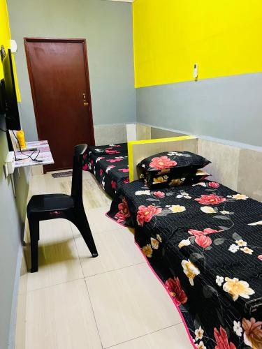 a room with two beds and a chair in it at Homestay/Bilik Teluk Gading in Kuala Rompin