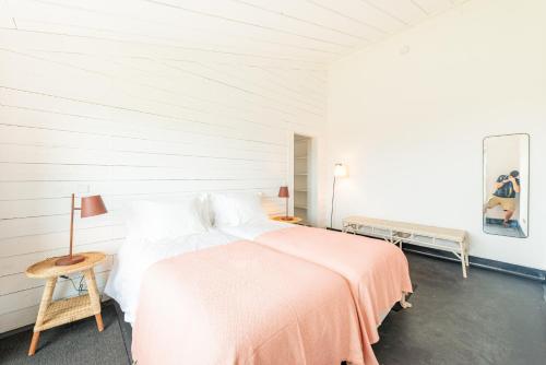 Dormitorio blanco con cama con manta rosa en Casas da Prainha D en Companhia de Baixo