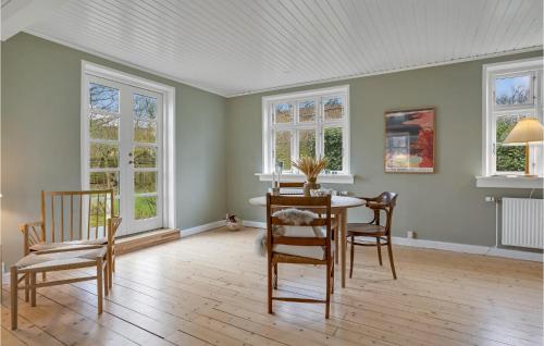 uma sala de jantar com mesa, cadeiras e janelas em Awesome Home In Sams With Wifi em Nordby