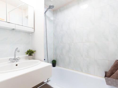 a white bathroom with a sink and a tub at Appartement Saint-Lary-Soulan, 2 pièces, 6 personnes - FR-1-296-158 in Saint-Lary-Soulan