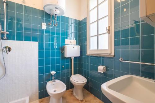 Baño de azulejos azules con aseo y lavamanos en Agenzia Vear - Osti 100, en Lido delle Nazioni
