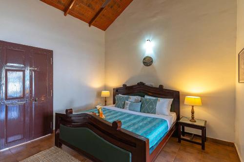 a bedroom with a bed and two lamps and a door at Misty Barn - "Your Poolside Escape Awaits" in Chikmagalur