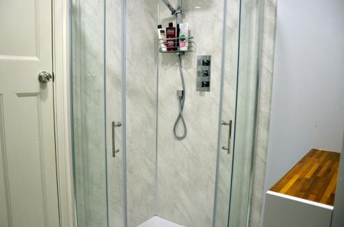 a shower with a glass door in a bathroom at 5 bedroom sunlit family house with garden in Redbridge