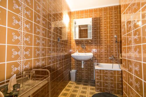 a bathroom with brown tiled walls and a sink at Statek Losiny in Velké Losiny