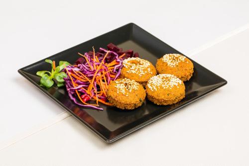 a black plate of food with donuts and a salad at Golden Time Hotel in Braşov