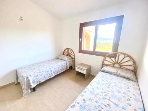 een slaapkamer met 2 bedden en een raam bij Villetta Nibbaru in Budoni