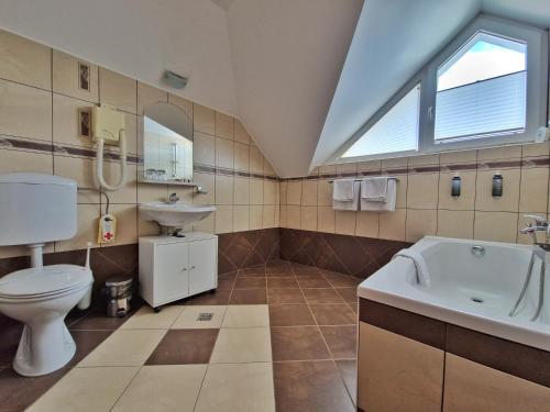 La salle de bains est pourvue de toilettes, d'un lavabo et d'une baignoire. dans l'établissement Penzion Kovac, à Radovljica