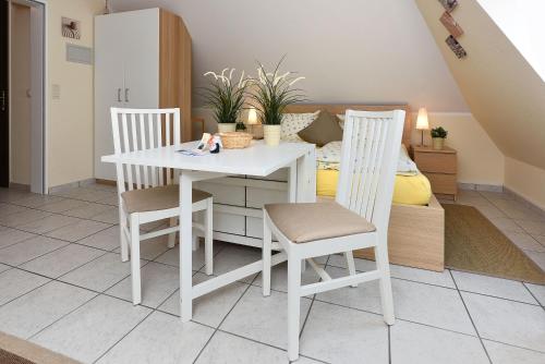 a white dining room table with two chairs and a bed at Apartment Typ C im DG, Haus Friedeburg, Carolinensiel in Wittmund