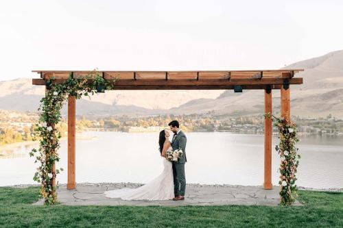 a bride and groom kissing under an arch with a lake at Rum Away with Me #303 in Chelan