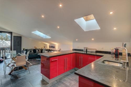 une cuisine avec des armoires rouges et un comptoir dans l'établissement APARTMENT LES DRUS - Alpes Travel - Chamonix - Sleeps 6, à Chamonix-Mont-Blanc