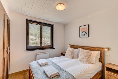 une chambre avec un lit avec des draps blancs et une fenêtre dans l'établissement APARTMENT LES DRUS - Alpes Travel - Chamonix - Sleeps 6, à Chamonix-Mont-Blanc