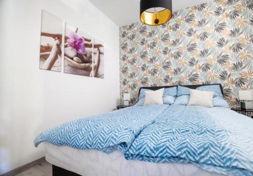 een slaapkamer met een bed met een blauw dekbed bij Club Panorama Lakeside Apartman in Alsóörs