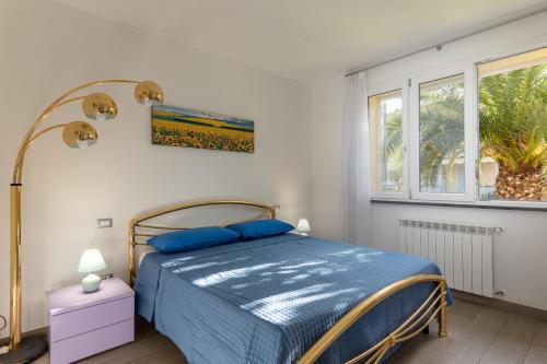 a bedroom with a bed with blue sheets and a window at Casa Pineta in Follonica