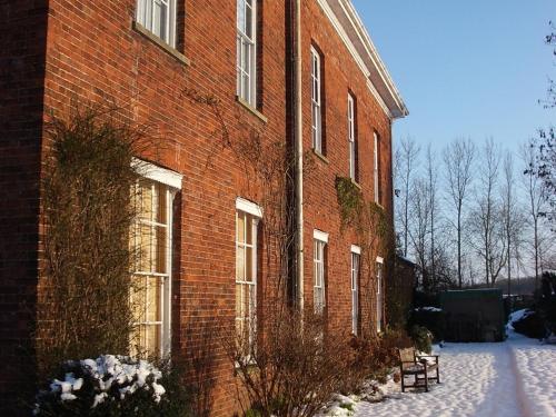 a large red brick building with snow on the ground at Glebe House Muston in Muston