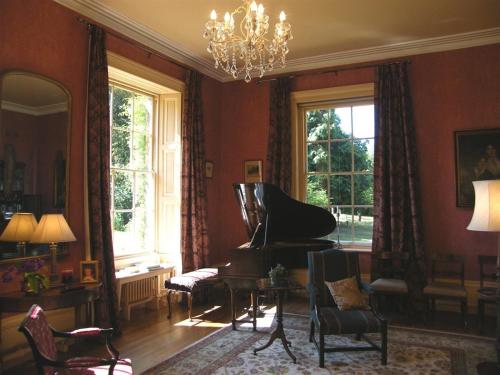 a living room with a piano and a chandelier at Glebe House Muston in Muston