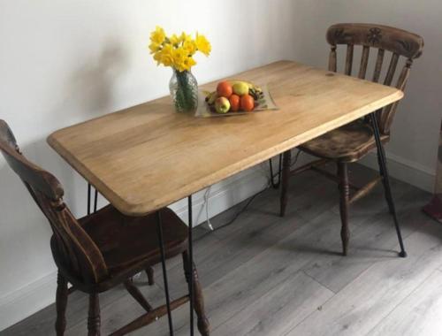 a wooden table with a bowl of fruit and a vase of flowers at Loughor Annnex, Llangennech , Wales in Llangennech
