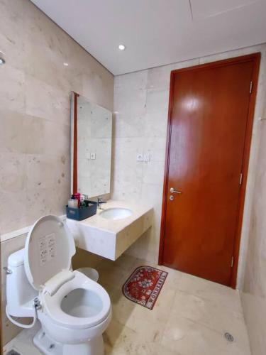 a bathroom with a toilet and a sink and a brown door at Senopati Penthouse Luxury 2 Bedroom Full Furnished SCBD Area in Jakarta