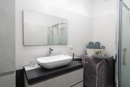 uma casa de banho com um lavatório branco e um espelho. em Casa Baronessa em Acireale