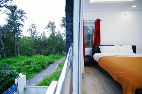 a bedroom with a bed and a balcony with a window at GV Resort in Yercaud
