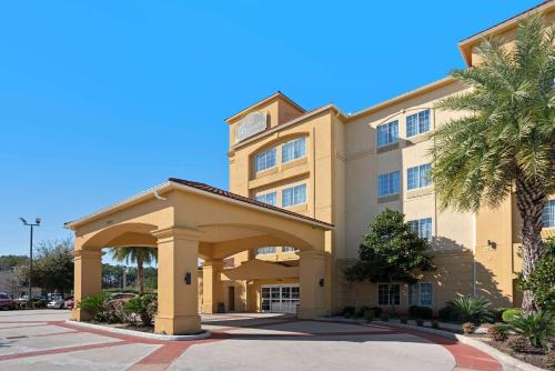 a large building with a palm tree in front of it at La Quinta by Wyndham Houston IAH Bush Intl Airport E in Humble