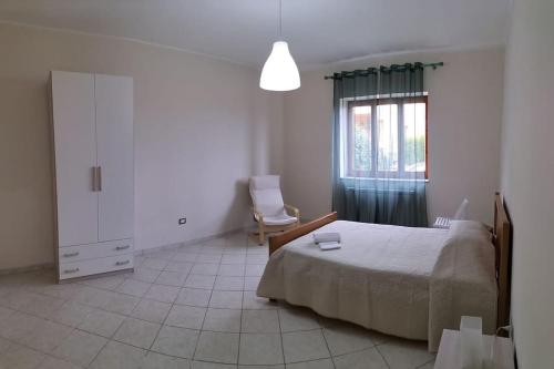 una camera con un letto e una sedia e una finestra di Appartamento i Gelsi a Praia a Mare