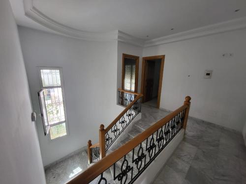 a staircase in a house with white walls and wooden railings at Duplex l ambassadeur in La Marsa
