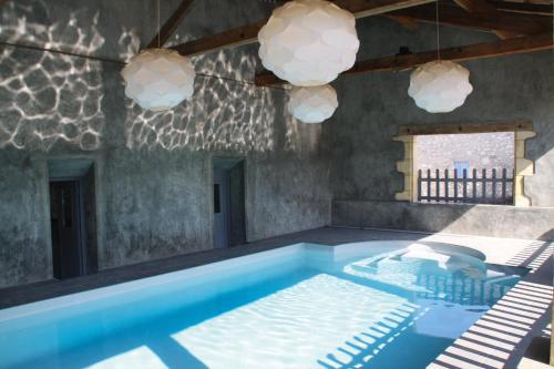 - une piscine dans une pièce avec des chaises et des lumières dans l'établissement Gîtes du Château de Panisseau, à Thénac