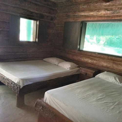 two beds in a room with two windows at Room in Cabin - Cabins Sierraverde Huasteca Potosina Green Cabin in Damían Carmona