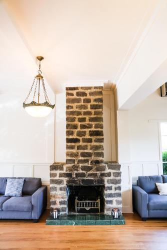 a living room with a stone fireplace and blue couches at Elizabethan Lodge in Melbourne