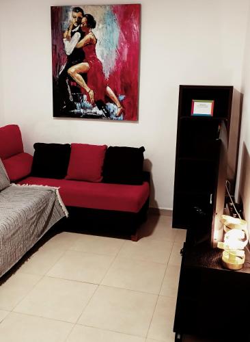a living room with a red couch and a painting at Tarancon Suite Exclusivo in Tarancón