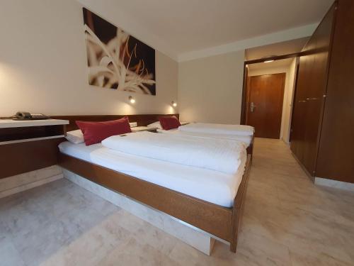 a bedroom with a large bed with white sheets and red pillows at Landhaus Oberaurach in Oberaurach