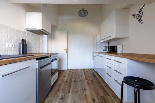 een keuken met witte kasten en een houten vloer bij Appart Premium aux Portes de Strasbourg avec Parking Privé in Schiltigheim