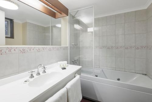 uma casa de banho branca com uma banheira e um lavatório em Elizabethan Lodge em Melbourne
