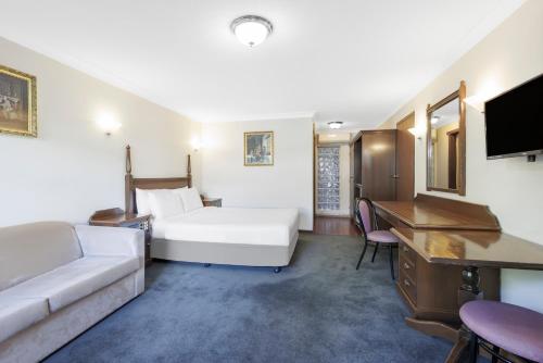 a hotel room with a bed and a desk at Elizabethan Lodge in Melbourne