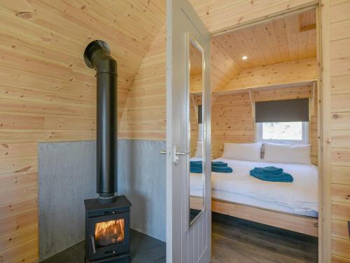 a bedroom with a wood stove in a log cabin at Creyr Glas Pod -uk41796 in Hirnant