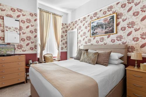 1 dormitorio con 1 cama grande y papel pintado de flores rosas en Melba House, en Torquay