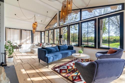 a living room with blue furniture and large windows at Villa du Douanier Nature d'Exception Proche Centre Ville et Vue sur le Golfe du Morbihan in Vannes