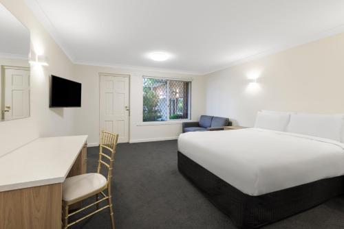 une chambre d'hôtel avec un grand lit blanc et une cuisine dans l'établissement Elizabethan Lodge, à Melbourne