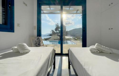 twee bedden in een kamer met uitzicht op een zwembad bij Villa Saphora Sea Front Villa in Évyiros