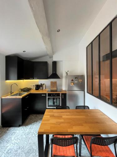 une cuisine avec une table en bois et des armoires noires dans l'établissement T2 de 40 m2 - facile d’accès, lumineux et au calme, à Saint-Genest-Lerpt