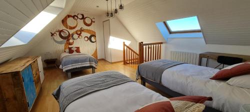a attic room with two beds and a window at Relais des îles Saint Marcouf in Saint-Marcouf