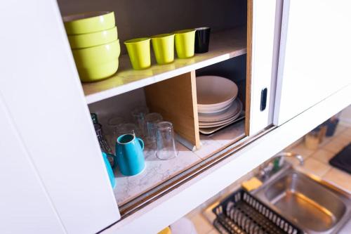 une armoire remplie de assiettes, de bols et d'un évier dans l'établissement Studio Voltaire au coeur de Jaurès, à Belfort