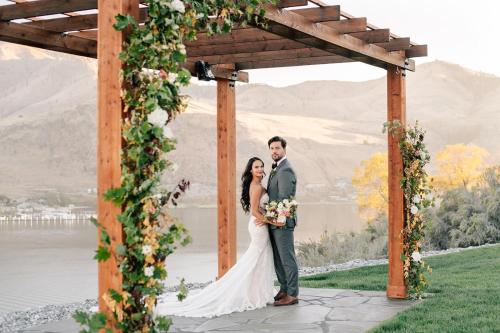 a bride and groom standing under an arch with flowers at Here Comes the Sun #123 in Chelan