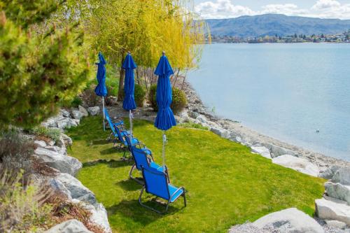 a row of blue chairs and umbrellas next to the water at Downtime #124 in Chelan