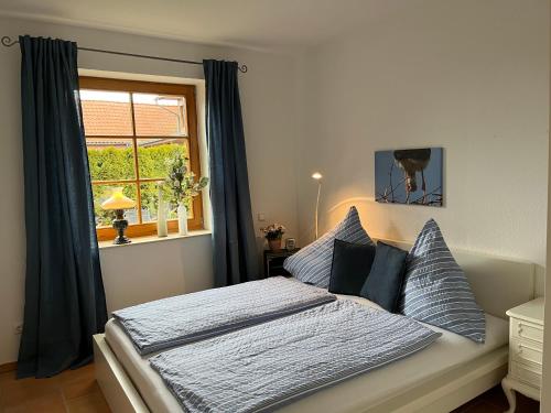 a bedroom with a bed with blue curtains and a window at Elb Nest Gästehaus in Neu Darchau