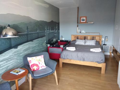 a bed and a chair in a room with a painting at OFERTA ESPECIAL ÚLTIMA HORA - SARAKATUA15 - vistas espectaculares - familias y parejas - 2 dormitorios independientes - amplio salón cocina comedor - tarjeta parking OTA GRATIS - Julio y agosto estancia mínima 7 noches de domingo a domingo - in Zarautz