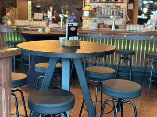 a table in a restaurant with stools and a bar at Hotel Hulsman in Venray