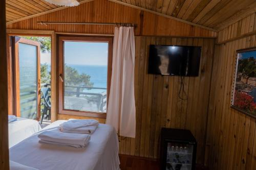a bedroom with a bed and a tv and a window at Tree Houses Hotel in Fethiye