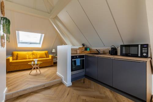 a kitchen and living room with a yellow couch at Appart Cosy Privé Avec parking gratuit aux portes de Strasbourg in Hoenheim